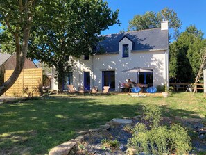 A house with a covered patio, a lawn, and a stone pathway. - House near beach, 3 double bedrooms with private bath. View of château. (Sarzeau)