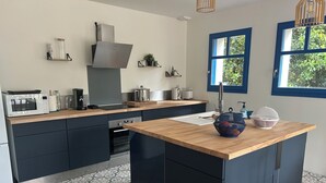 A modern kitchen with a central island, built-in appliances, and a window with a view of greenery. - House near beach, 3 double bedrooms with private bath. View of château. (Sarzeau)