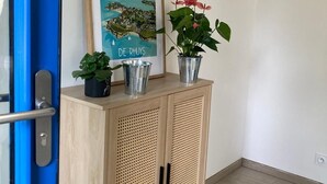 A wooden cabinet with perforated doors, a framed picture of a coastal scene, and two potted plants. - House near beach, 3 double bedrooms with private bath. View of château. (Sarzeau)