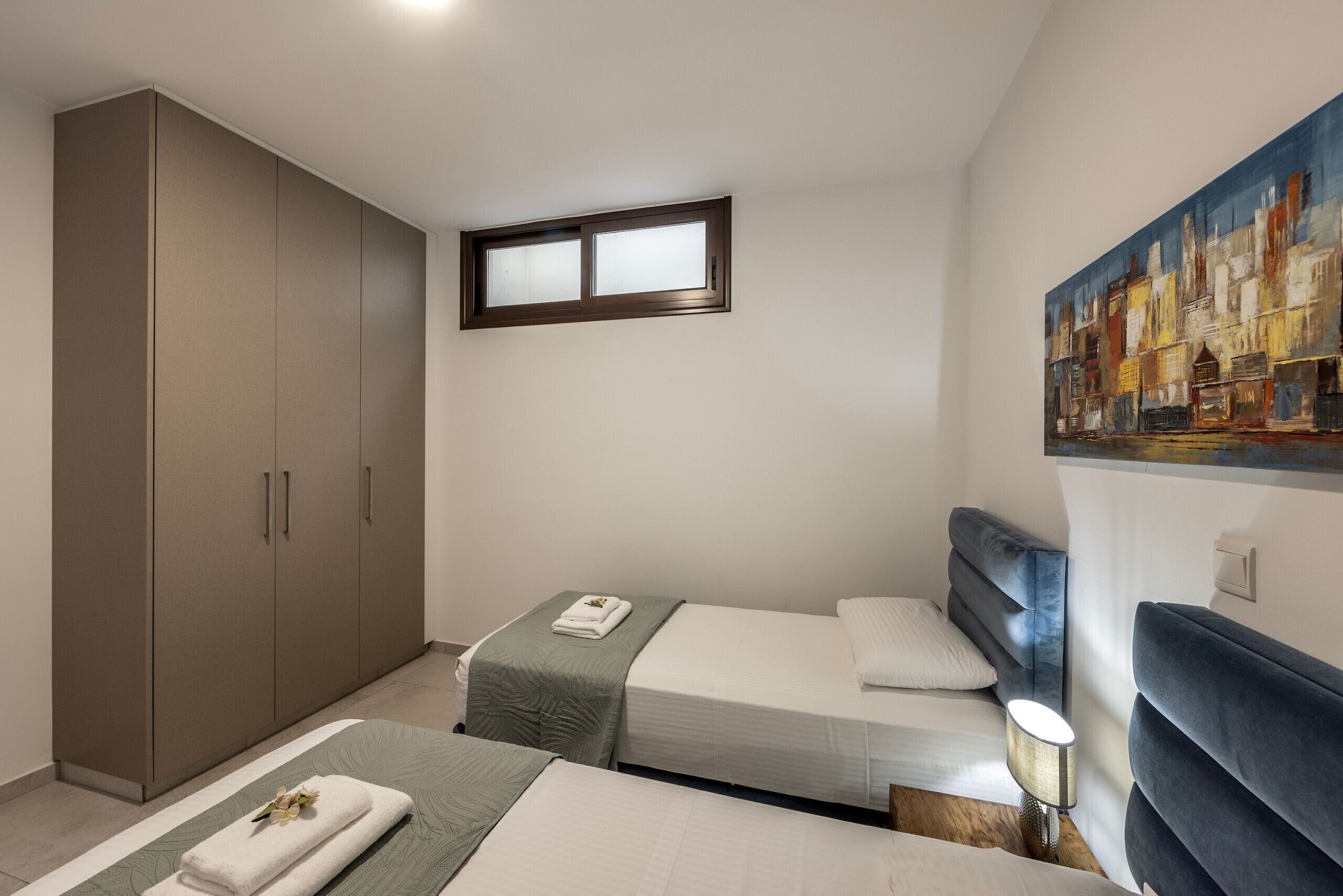 Un dormitorio con dos camas, un armario, un cuadro y una ventana.