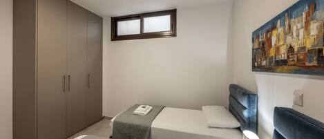 Un dormitorio con dos camas, un armario, un cuadro y una ventana.