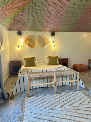 A bedroom with a bed, bedside tables, a bench, and a patterned ceiling. - Le Rubis Oriental (Marrakech)