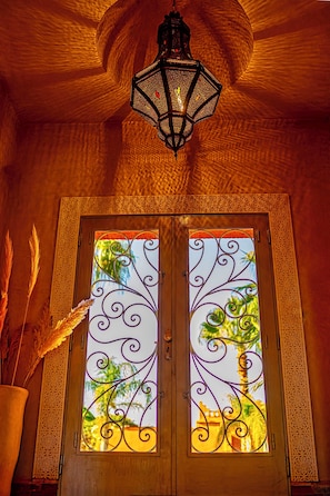 A door with intricate metalwork and a view of palm trees through the glass. - Le Rubis Oriental (Marrakech)