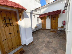 Un patio con puertas de madera, un extintor y mobiliario exterior.