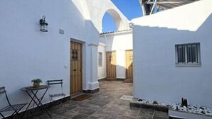 A courtyard with white walls, a tiled floor, and a small table with chairs. - Antonio Parra II Tourist Apartments (Jerez de la Frontera)