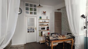 Un comedor con una mesa de madera, sillas, un armario blanco con estantes, un reloj y una ventana con una planta.