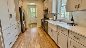 A modern kitchen with white cabinetry, a stainless steel refrigerator, and a gas stove. - Wharf Street Coastal Escape - 3BR Old Town Luxury (Bluffton)