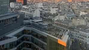 A cityscape with modern buildings, including a tall skyscraper and a glass-fronted building with a rooftop terrace. - Exceptional family duplex with breathtaking views of Paris! (Paris)