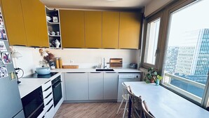 A modern kitchen with wooden flooring, a dining area with a table and chairs, and a large window with a city view. - Exceptional family duplex with breathtaking views of Paris! (Paris)