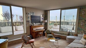A spacious living room with a piano, comfortable seating, and large windows offering a city view. - Exceptional family duplex with breathtaking views of Paris! (Paris)