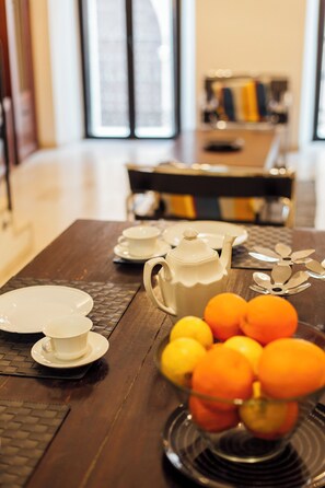 A wooden dining table with white teapots, cups, and a bowl of oranges. - Buen Suceso Las Setas Sevilla (Seville)