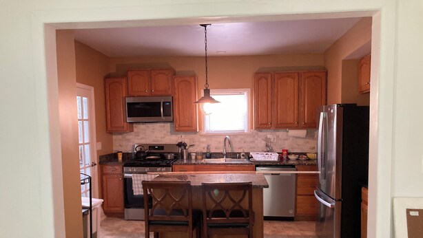 A kitchen with wooden cabinets, a stainless steel refrigerator, a microwave, and a stove. - CHARMING 3-BEDROOM HOUSE/ A ROOM FOR RENT, with WiFi, AC in lovely Cleveland. (Cleveland)