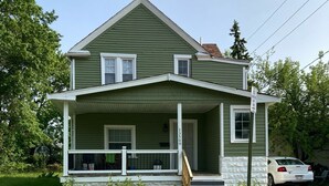 A two-story house with a green exterior, a front porch, and a visible address number. - CHARMING 3-BEDROOM HOUSE/ A ROOM FOR RENT, with WiFi, AC in lovely Cleveland. (Cleveland)