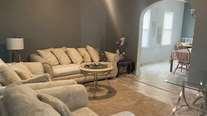 A living room with a beige sofa, a glass coffee table, and a dining area with a wooden table and chairs. - CHARMING 3-BEDROOM HOUSE/ A ROOM FOR RENT, with WiFi, AC in lovely Cleveland. (Cleveland)