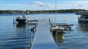 Eine Holzsteg, der sich in ruhiges Wasser erstreckt, mit Booten an beiden Enden.