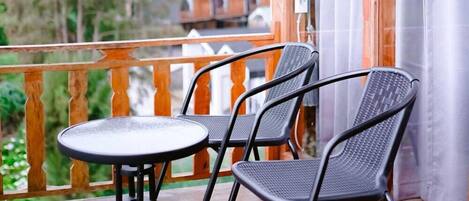 A wooden balcony with a table and two chairs.