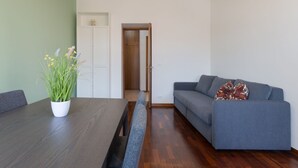 Uma sala de estar moderna com uma mesa de jantar de madeira, um sofá cinza e um vaso com planta.