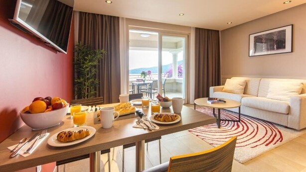 Ett modernt hotellrum med en matplats, en soffa och en balkong med utsikt.