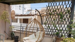 A balcony with a hanging chair, potted plants, and a lattice fence.