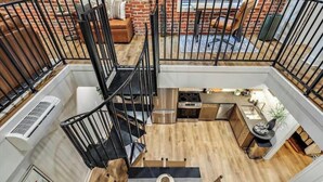 Un apartamento moderno estilo loft con cocina, comedor y una escalera que conduce a un nivel superior.