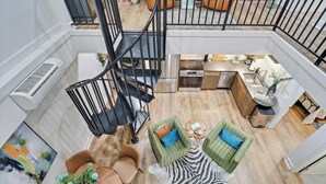 Amplio loft con entrepiso, escalera y zona de cocina.