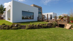 A modern house with a large glass window, a stone fireplace, and a wooden deck. - BeGuest Penedo Escape Sea Suite 3 (Ulgueira)
