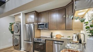 A modern kitchen with stainless steel appliances, wooden cabinets, and a wooden countertop with glasses.