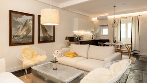 A modern living room with a sofa, a coffee table, a chair, and a dining area with a table and chairs. - Modern apartment with private outdoor space (Trieste)