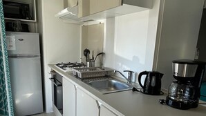 A compact kitchen with a refrigerator, stove, sink, and coffee maker. - Mobile home P007 6 persons (Vendays-Montalivet)