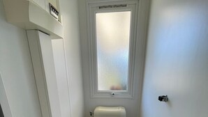 A small, narrow bathroom with a toilet, a window, and a toilet paper holder. - Mobile home P007 6 persons (Vendays-Montalivet)
