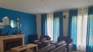 Una sala de estar con pared azul, chimenea, sofás de cuero y una mesa de centro de madera.