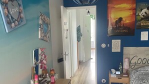 Un dormitorio con una cama de madera, un escritorio con una silla, una lámpara colgante y un cartel de un león en la pared.