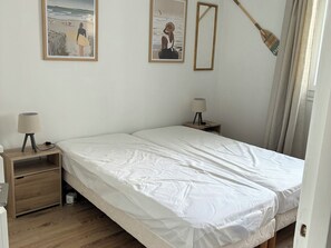 Une chambre à coucher avec un lit, deux tables de chevet, une lampe sur chacune, et deux tableaux encadrés accrochés au mur.