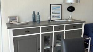 A modern kitchen with grey cabinets, a black chair, and a framed picture on the counter.