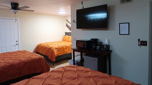 A hotel room with two beds, a TV, a ceiling fan, a desk with a microwave, and a small refrigerator. - Hopi Room #2                                 . (Williams)