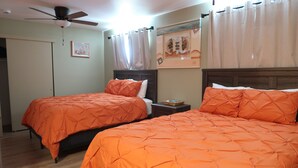 A bedroom with two beds, a ceiling fan, a framed picture, and a window with curtains. - Hopi Room #2                                 . (Williams)