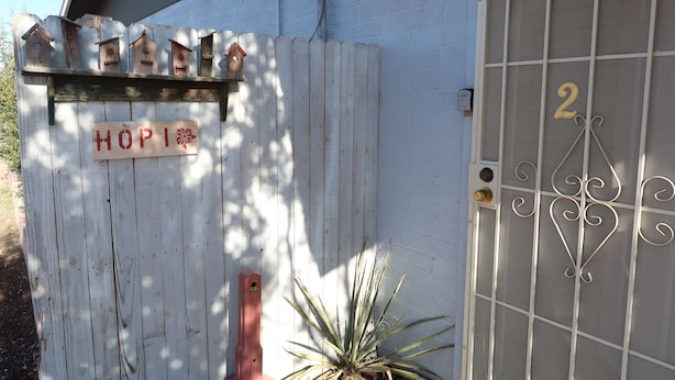 A white wooden fence with birdhouses and a sign that says 'HOPI.' - Hopi Room #2                                 . (Williams)