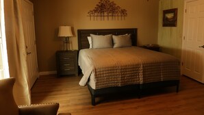 A bedroom with a bed, nightstand, lamp, and a wall-mounted artwork.