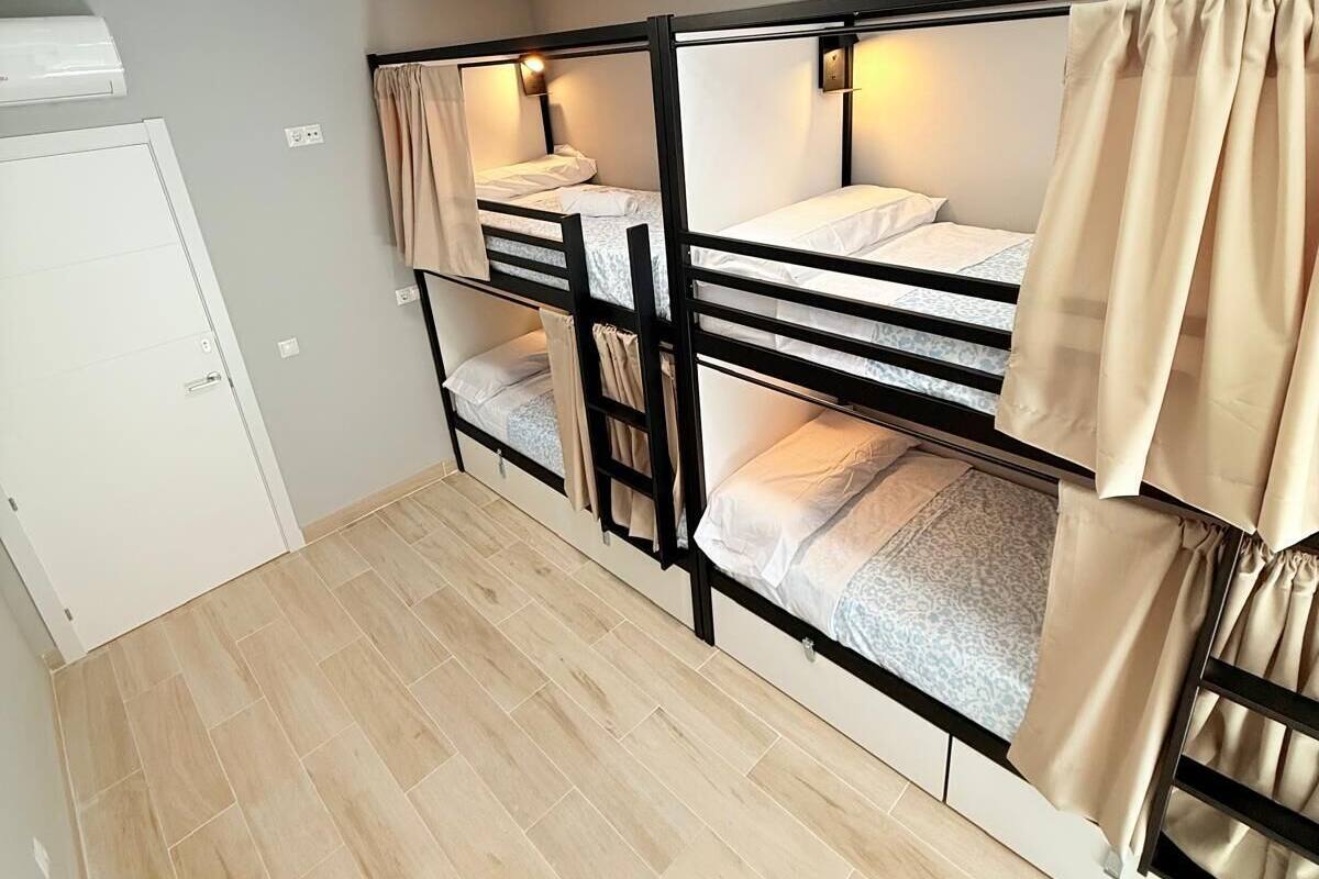 Une chambre de dortoir avec des lits superposés, une porte blanche et un sol carrelé.
