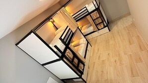 Quarto compacto com cama, uma mesinha e uma cadeira.
