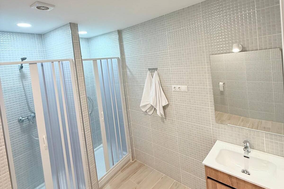 Une salle de bain moderne avec une douche à parois de verre, un meuble-lavabo en bois et un grand miroir.