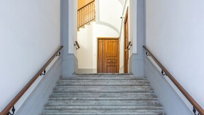 A marble staircase with wooden handrails leading to a wooden door at the top. - Urban Base Garibaldi by NapoliApartments (Naples)