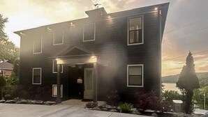 A two-story house with a dark exterior, a front porch, and a driveway.