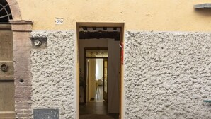 A narrow doorway leading into a building with a textured wall and a number plaque.