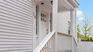 A white two-story house with a porch, a front door, and a mailbox.