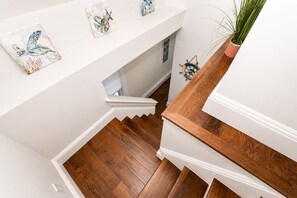 A wooden staircase with white walls and artwork.
