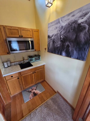 A compact kitchen with wooden cabinets, a microwave, a coffee maker, and a toaster.