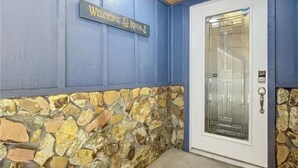A stone wall with a welcome sign and a door with a glass panel.
