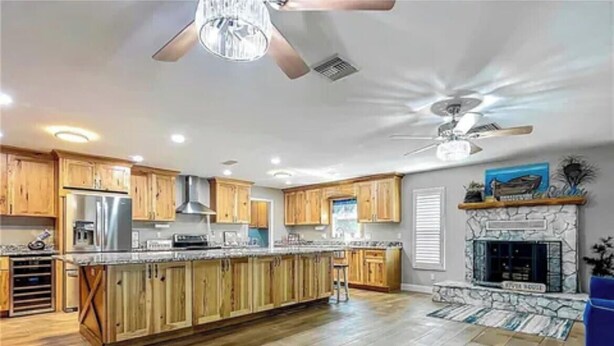 A spacious kitchen with wooden cabinets, a central island, and a fireplace.