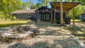 A house with a covered patio, a fire pit, and a gravel driveway.
